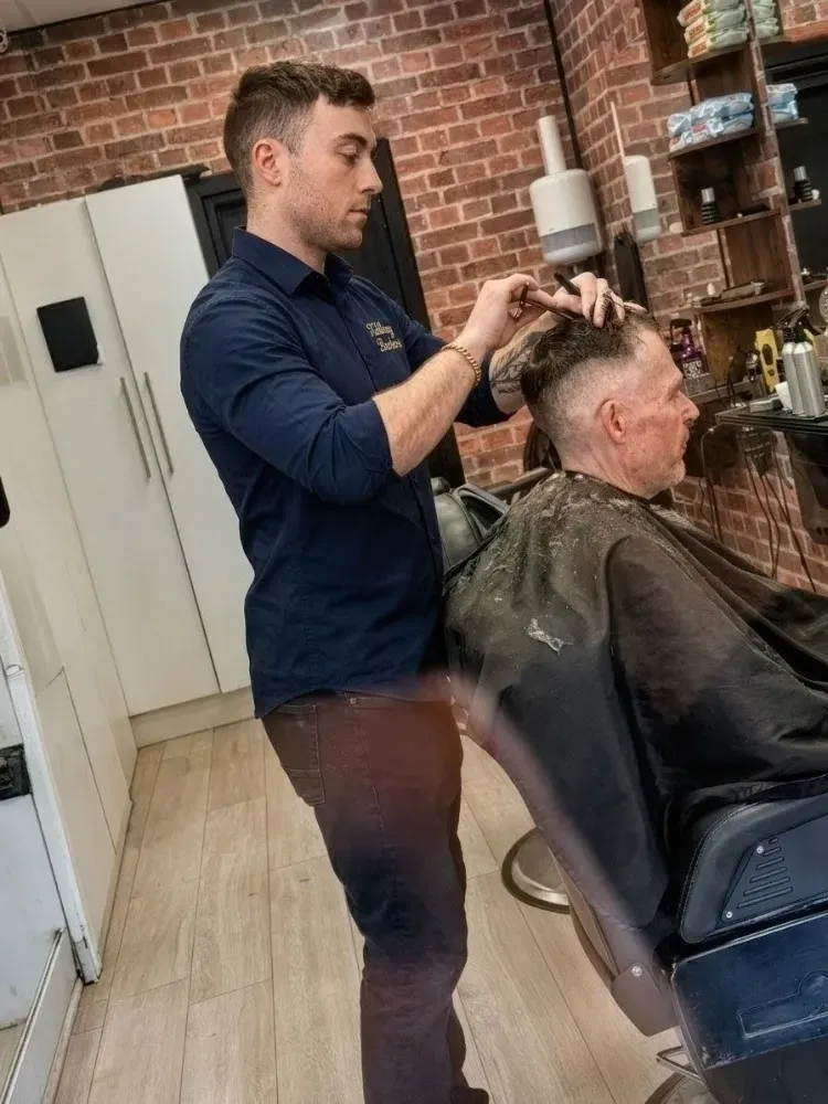 Master barber performing a precise scissor haircut and detailing at Killiney Barbers